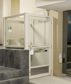 A platform wheelchair lift installed beside a flight of stairs.