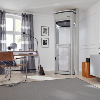 A modern home office with a personal elevator installed near the doorway.