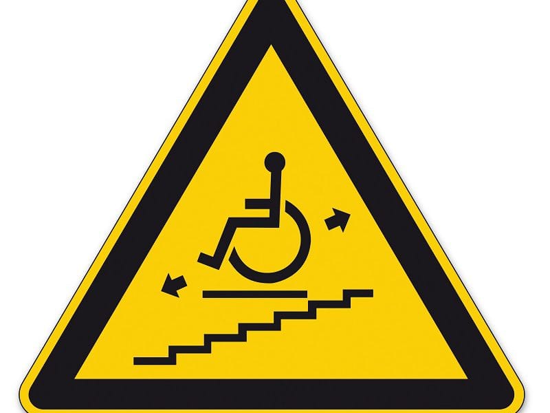 Triangular caution sign indicating wheelchair ramp or accessible route ahead.
