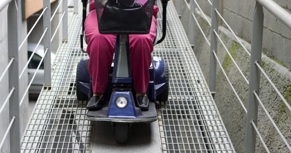 Person in a motorized wheelchair using a ramp for accessibility.