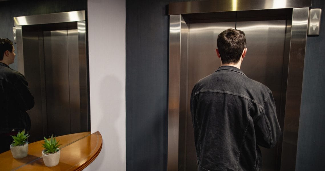 Man waiting in front of closed elevator doors.