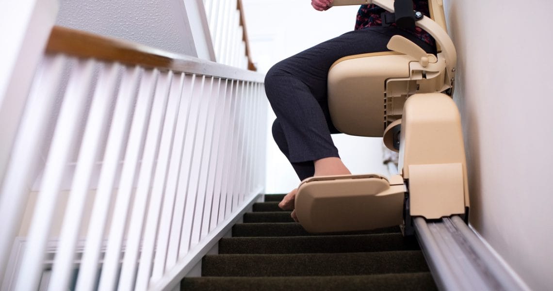 Person using a stairlift to ascend a staircase.